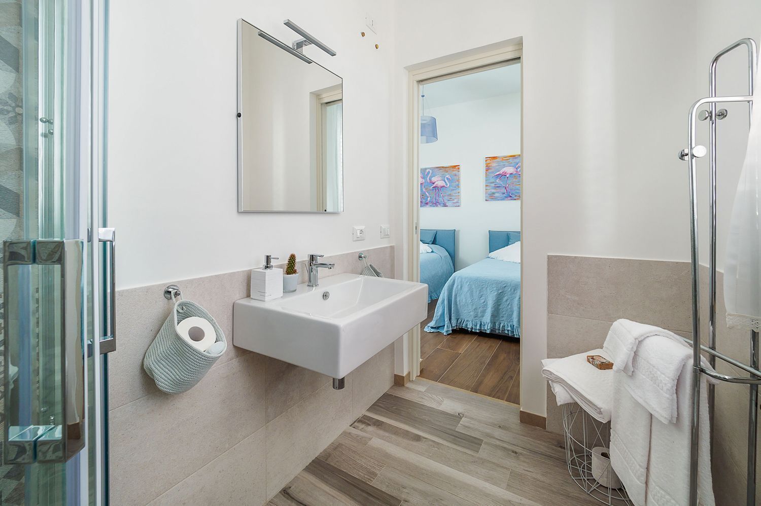 A modern bathroom with a large sink, mirror, and glass shower enclosure.
