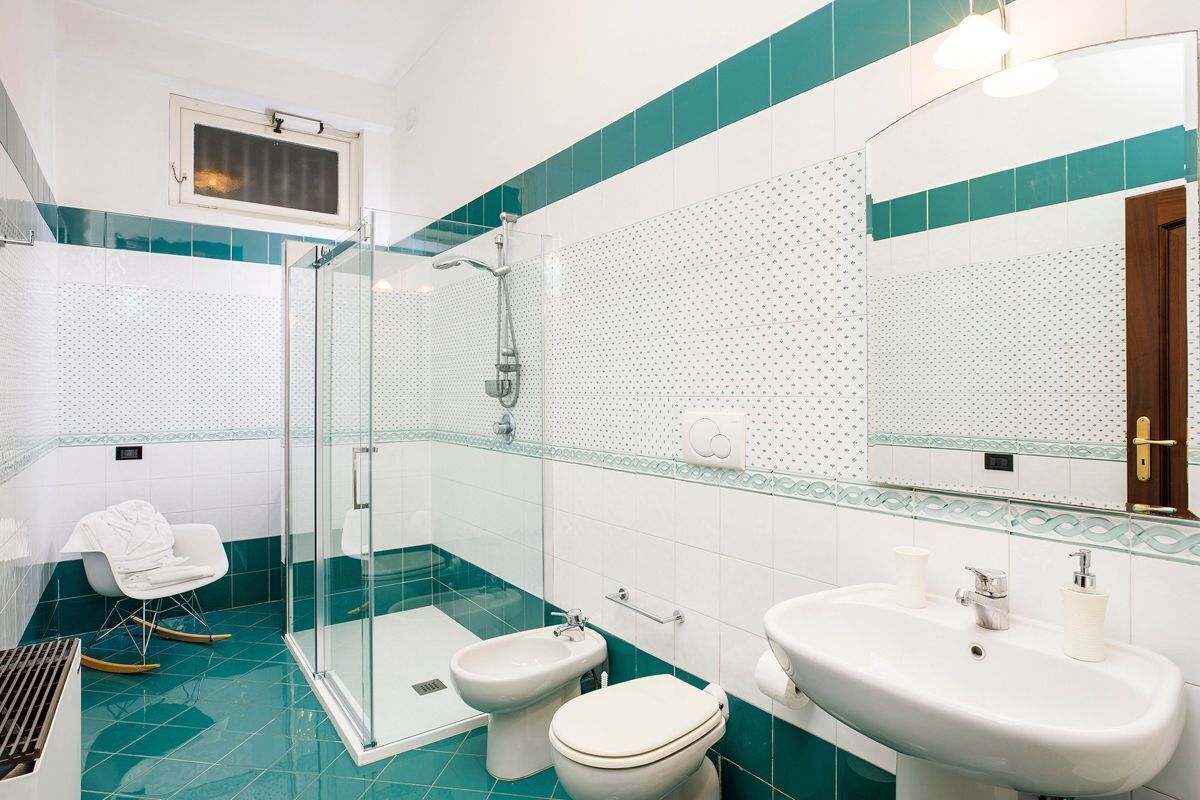 Une salle de bain avec une douche à parois de verre, des toilettes blanches et un lavabo avec un miroir au-dessus.