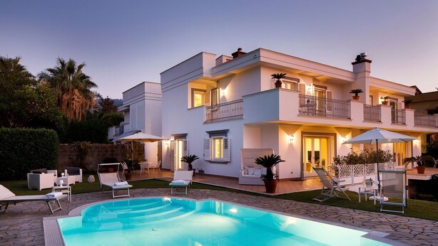 A modern two-story house with a swimming pool, outdoor furniture, and a well-lit balcony. - Villa Minerva - Three Bedroom Villa, Sleeps 10 (Sant'Agnello)