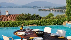 A dining table set for four with a view of a lake and mountains in the background. - Villa Meina - Four Bedroom Villa, Sleeps 8 (Meina)