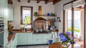 A kitchen with a stove, cabinets, and a view of the outdoors. - Villa Meina - Four Bedroom Villa, Sleeps 8 (Meina)
