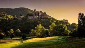 A castle on a hill with a golf course in the foreground.