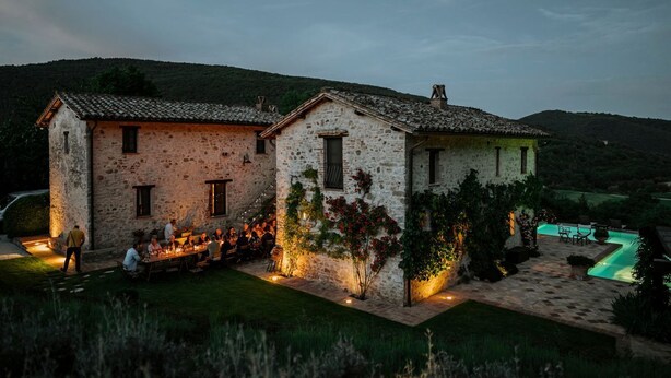 A stone building with a pool and outdoor seating area.