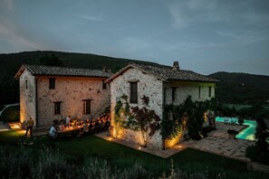 Ein Gebäude aus Stein mit Pool und Sitzgelegenheiten im Freien.