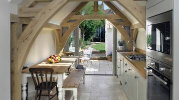 Une cuisine avec une table et des chaises en bois, un panier de fruits et une vue sur le jardin.