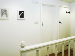 A hallway with white walls, a white railing, and two doors with black handles. - 2 bedroom accommodation in Winchester (Winchester)