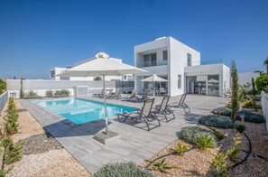 Una casa moderna con piscina, mobiliario exterior y un jardín bien cuidado.