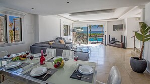 Una sala de estar moderna con comedor, una planta grande en maceta y vista al océano.