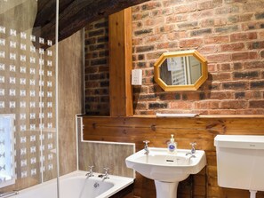 Une salle de bain avec un mur en bois, un miroir, un lavabo et une baignoire.