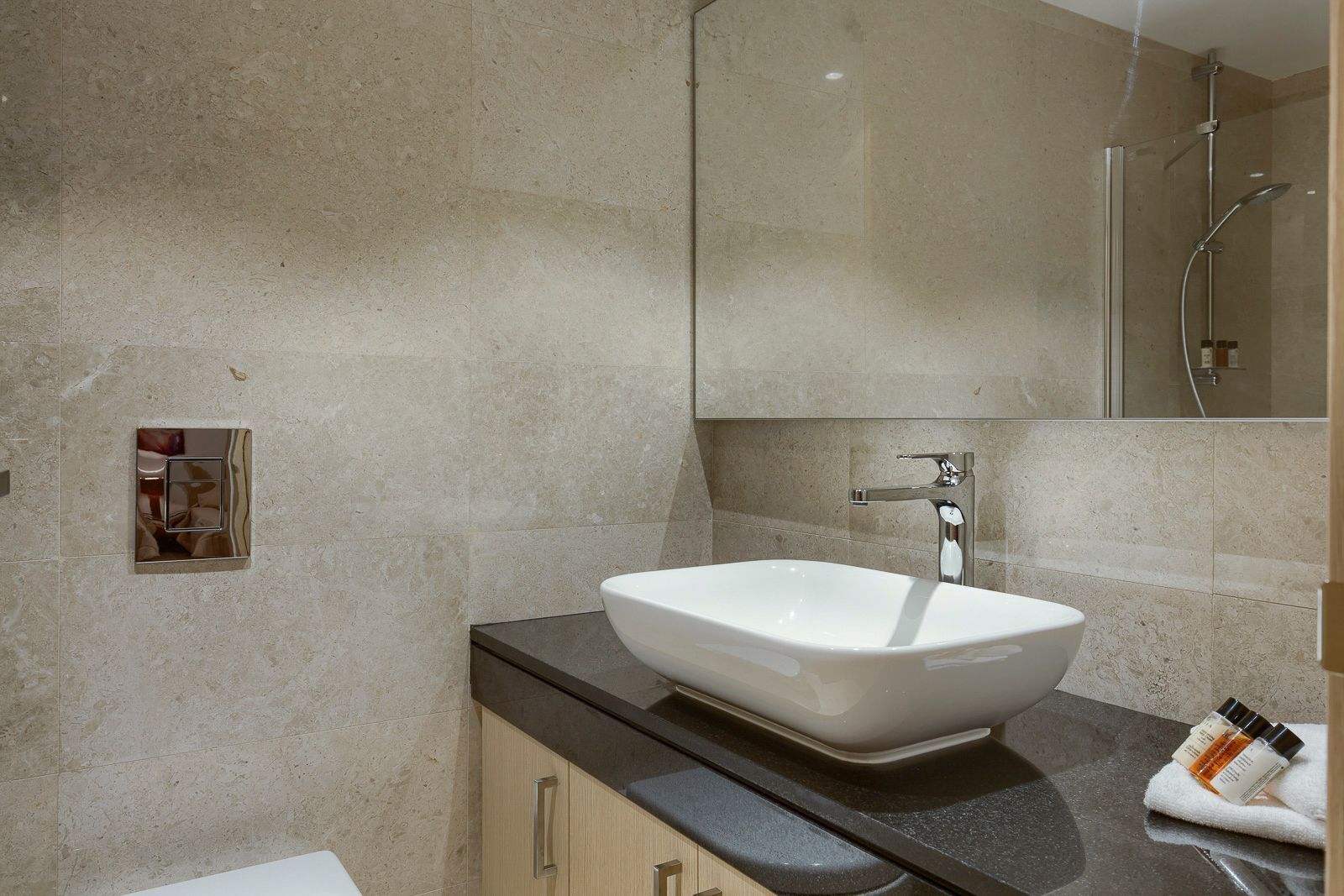 Een moderne badkamer met een groot, wit wastafel, een spiegel en een douche.