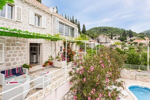 Une maison en pierre avec une piscine, un espace extérieur aménagé et une vue sur les collines environnantes.
