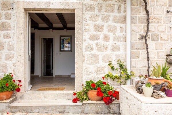 A stone building entrance with a door leading inside, potted plants, and a small table with decorative items. - Villa Toni - Five Bedroom Villa, Sleeps 10 (Orasac)