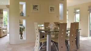 A dining area with a glass table, cushioned chairs, and framed artwork on the walls. - 3 bedroom accommodation in Lanreath, near Looe (Lanreath, near Looe)