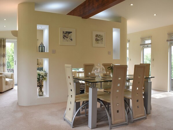 Un espace repas avec une table en verre, des chaises rembourrées et des œuvres d’art encadrées accrochées aux murs.