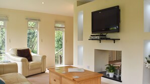 A living room with a sofa, a wooden coffee table, a television mounted on the wall, and a fireplace. - 3 bedroom accommodation in Lanreath, near Looe (Lanreath, near Looe)