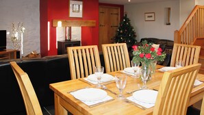 A dining area with a wooden table set for six, surrounded by chairs, with a Christmas tree in the background. - 3 bedroom accommodation in Ystrad Meurig (Ystrad Meurig)