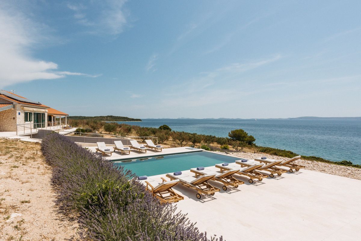 A poolside area with lounge chairs and a view of the sea.