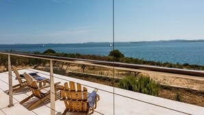 Un balcon avec des chaises en bois et vue sur la mer.