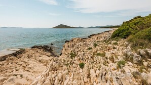 Un paysage côtier rocheux offrant une vue dégagée sur la mer et les collines lointaines.