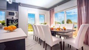 Eine moderne Küche mit integrierten Geräten und einer Essecke mit weißen Stühlen und einem für das Frühstück gedeckten Tisch.