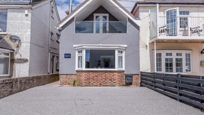 A two-story house with a prominent bay window, a satellite dish, and a sign indicating 'Ocean Beach'.