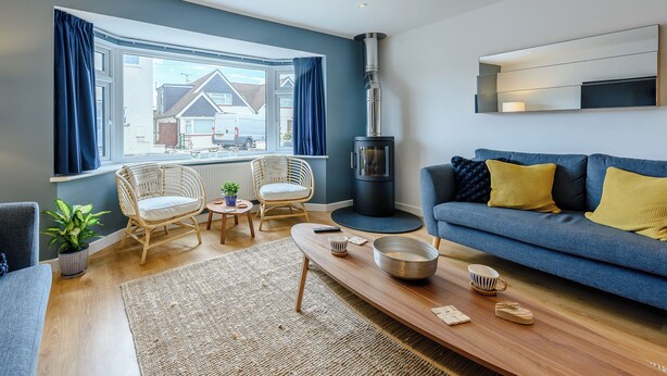 A modern living room with a sofa, chairs, a coffee table, and a wood-burning stove.