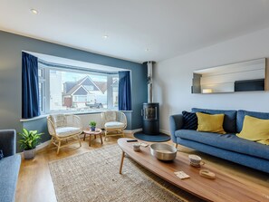 Uma sala de estar moderna com sofá, poltronas, mesa de centro e lareira a lenha.