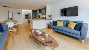 A modern living room with a sofa, coffee table, and a TV mounted on the wall.