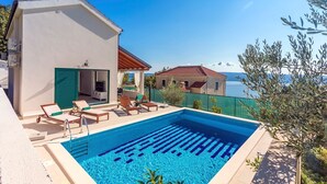 A swimming pool with lounge chairs and a view of the sea.