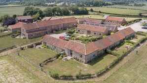 A large, rectangular stone building with a tiled roof, surrounded by a well-maintained lawn and a fence.