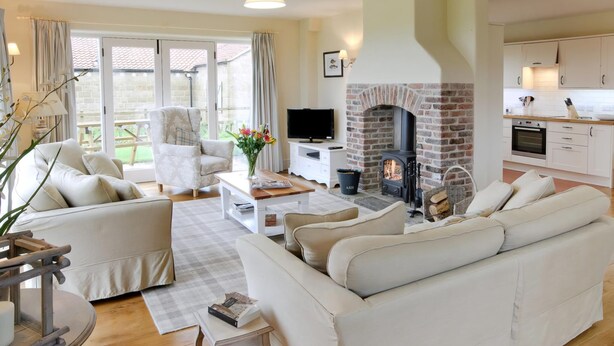 A spacious living room with a sofa, armchairs, a coffee table, and a fireplace.