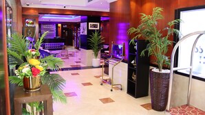 Un vestíbulo de hotel con una recepción, plantas en macetas y un área de descanso.