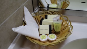 Un baño con una cesta de mimbre que contiene artículos de aseo, incluyendo una botella de champú, acondicionador y dos jabones.