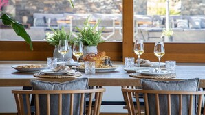 Une table à manger dressée avec des assiettes remplies de nourriture, des verres de vin et des plantes en pot.