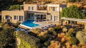 A modern house with a swimming pool, outdoor seating, and a stone patio. - Villa Elounda - Eight Bedroom Villa, Sleeps 17 (Elounda)