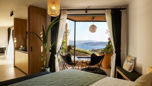 A bedroom with a large bed, a view of the sea, a balcony with chairs, and a dining area. - Villa Elounda - Eight Bedroom Villa, Sleeps 17 (Elounda)