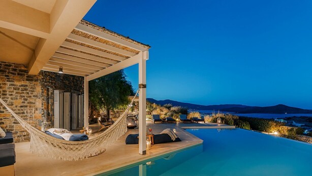 An infinity pool with a view of the sea and mountains, a hammock, and outdoor seating. - Villa Elounda - Eight Bedroom Villa, Sleeps 17 (Elounda)