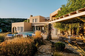 Eine moderne Villa mit Swimmingpool, Essbereich im Freien und einem gepflasterten Weg.