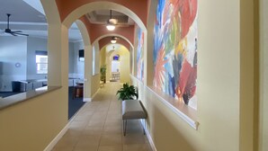 A hallway with arches, a bench, and a colorful mural on the wall.
