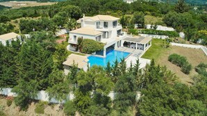 Una villa moderna con piscina, immersa nel verde e con montagne sullo sfondo.