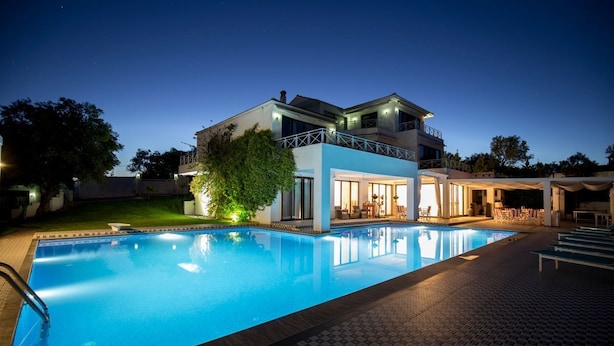 Una moderna casa a due piani con piscina, area salotto esterna e patio ben illuminato.