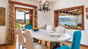 A dining area with a table, chairs, and a view of the sea. - Villa Tersanas - Four Bedroom Villa, Sleeps 9 (Livadi)