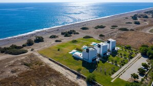 Vue aérienne d’une propriété côtière avec un bâtiment moderne comprenant deux grandes structures et une piscine.