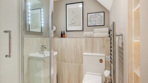 A modern bathroom with a glass shower enclosure, a white sink, a toilet, and a towel rack.