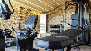 A gym with a stone wall, exercise equipment, and a wooden ceiling.