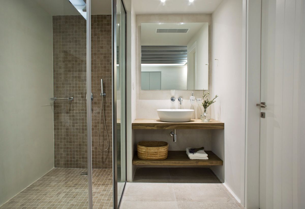 A modern bathroom with a glass shower enclosure, a large mirror, a vessel sink, and a wooden vanity.