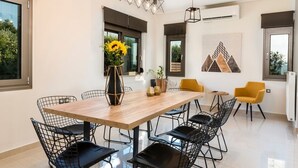 Un comedor moderno con una mesa de madera y sillas de estructura metálica negra, un jarrón con girasoles y una pieza de arte mural geométrica.