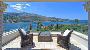 A balcony with wicker furniture and a view of a lake and mountains.