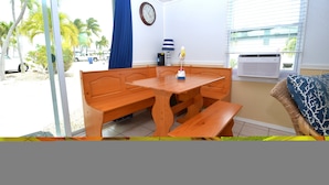 A room with a wooden bench table, a clock on the wall, and a window with blinds. - FL Keys Cottage with Ocean Views - Venture Out Unit 395 (Cudjoe Key)