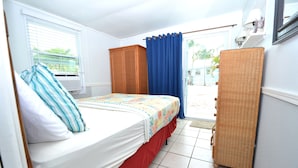 A bedroom with a bed, a wardrobe, and a wicker chair. - FL Keys Cottage with Ocean Views - Venture Out Unit 395 (Cudjoe Key)